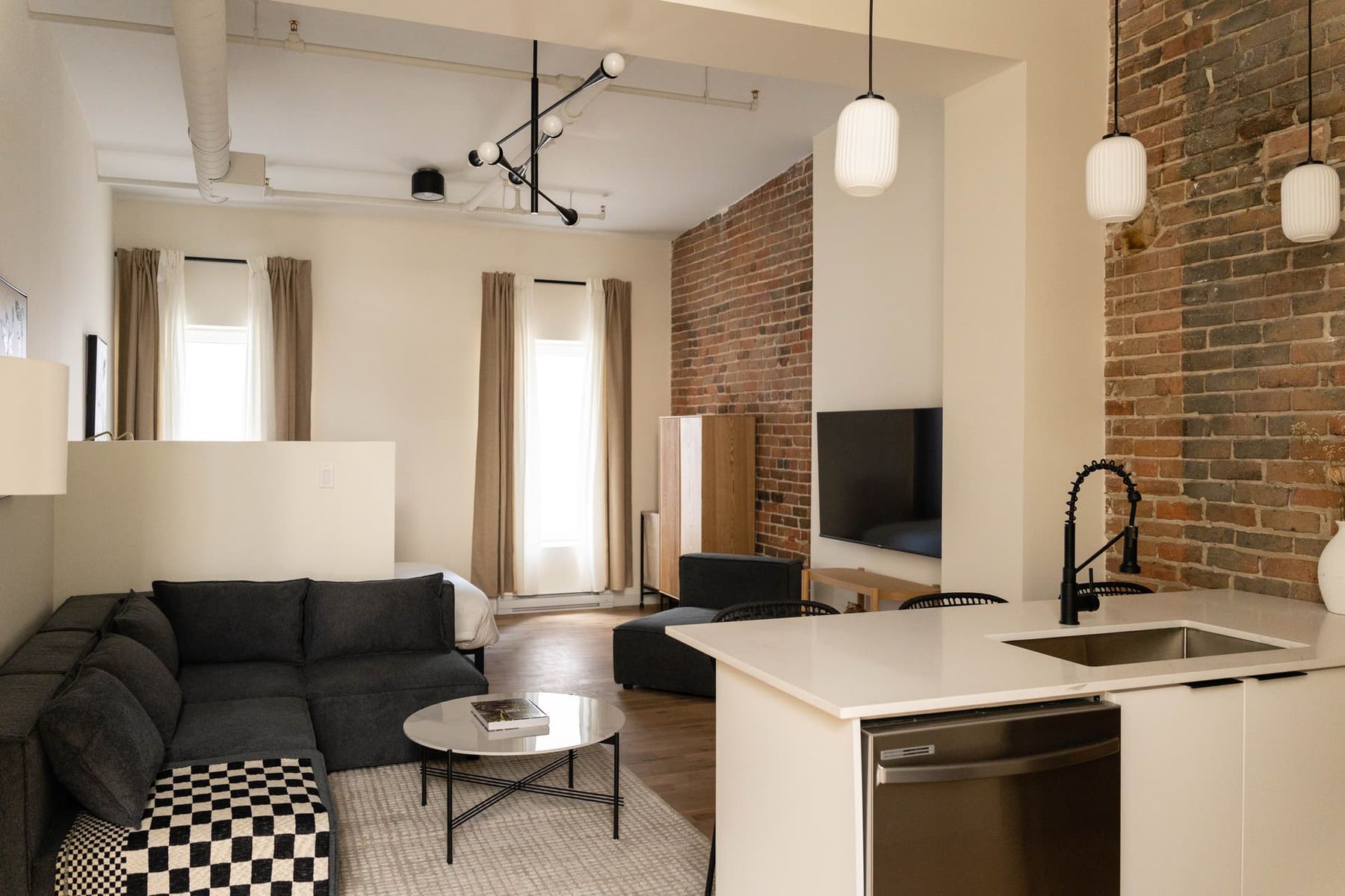 Loft avec mur de briques, salon et cuisine impeccables