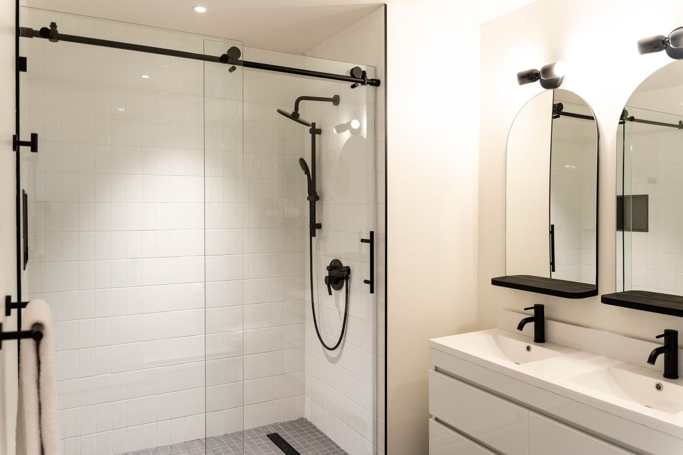 Salle de bain avec douche vitrée et double lavabo étincelants